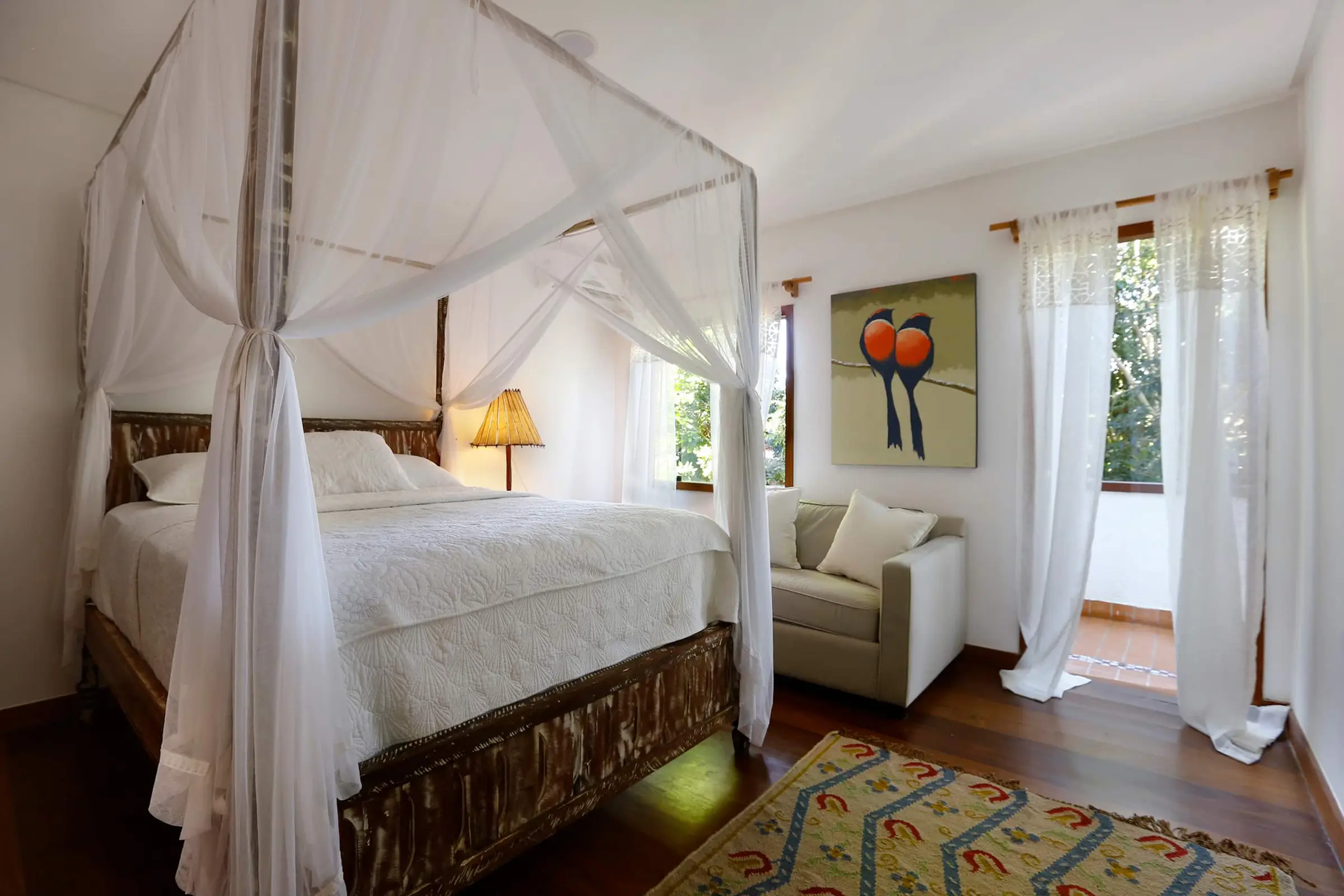 Quarto com cama de casal envolta em mosquiteiro branco