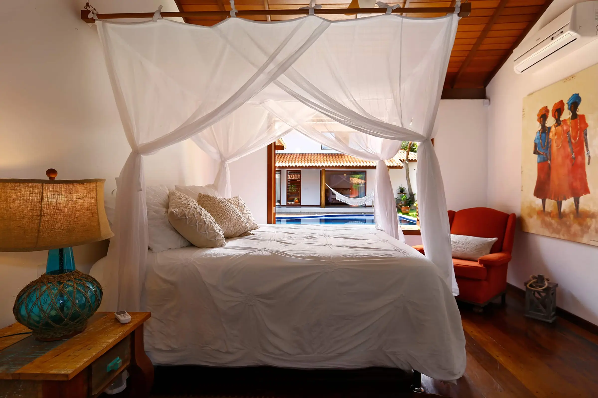 Quarto com cama com dossel e obra de arte colorida