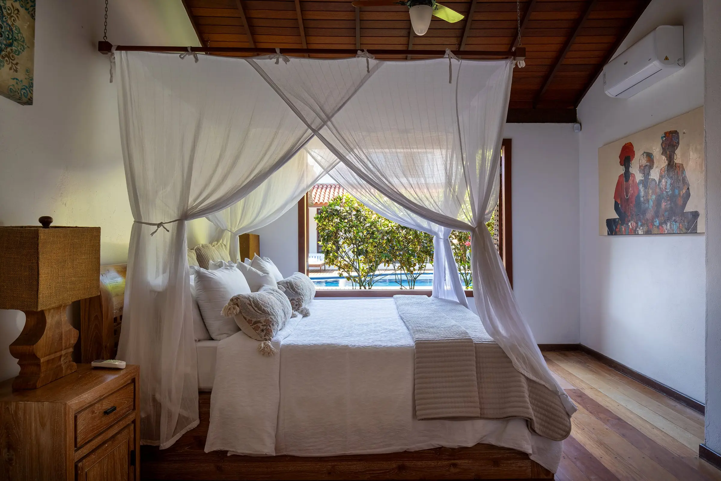Quarto com dossel branco e vista para a piscina