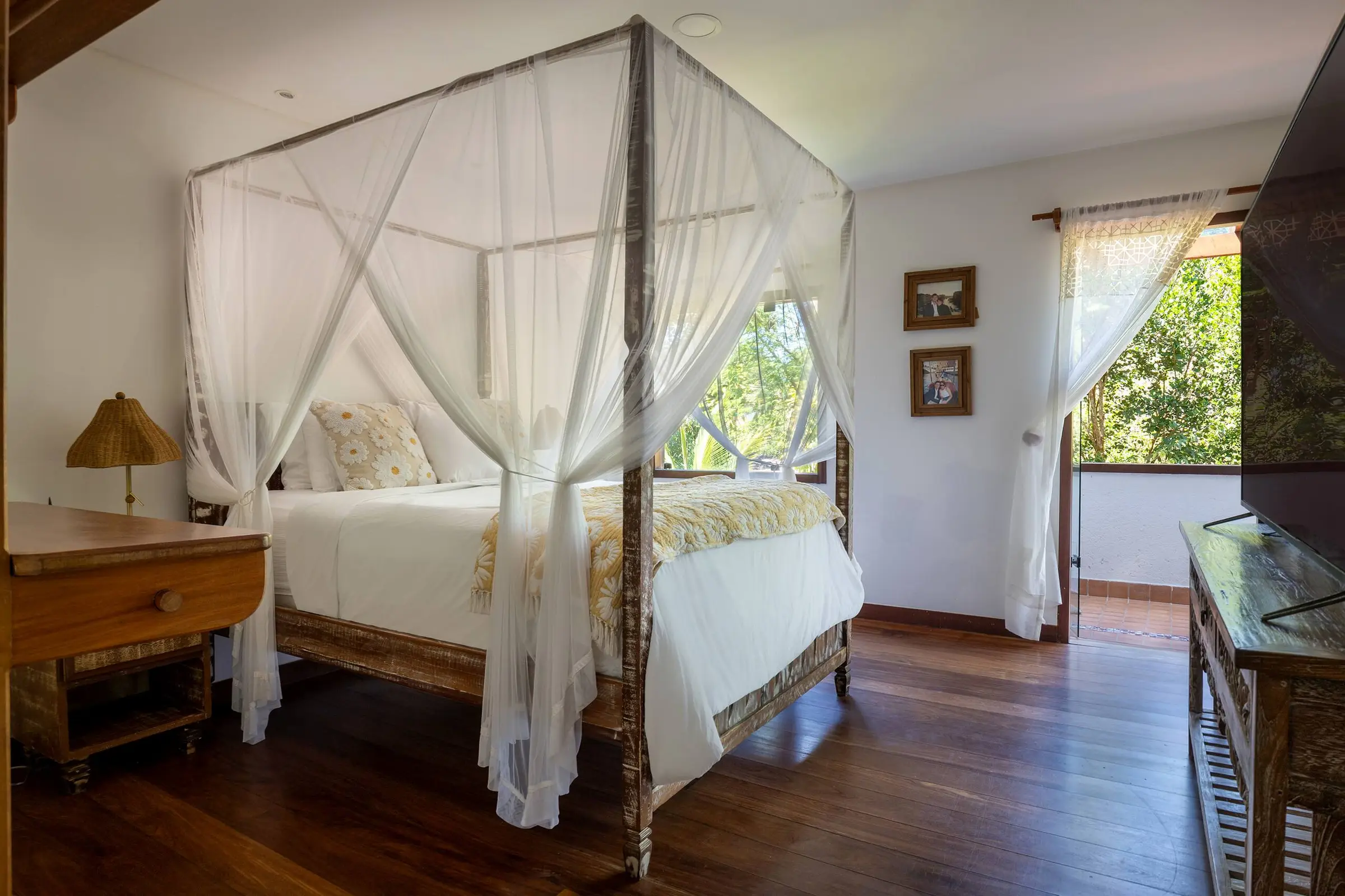 Quarto com cama de casal, cortinado branco e piso de madeira