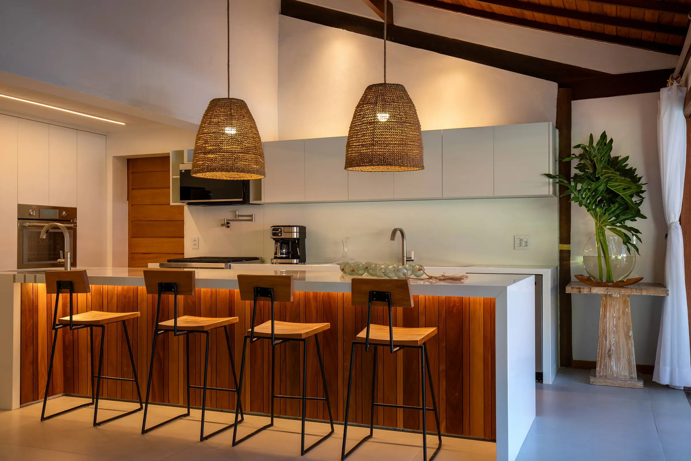 Cozinha com ilha central e banquetas de madeira