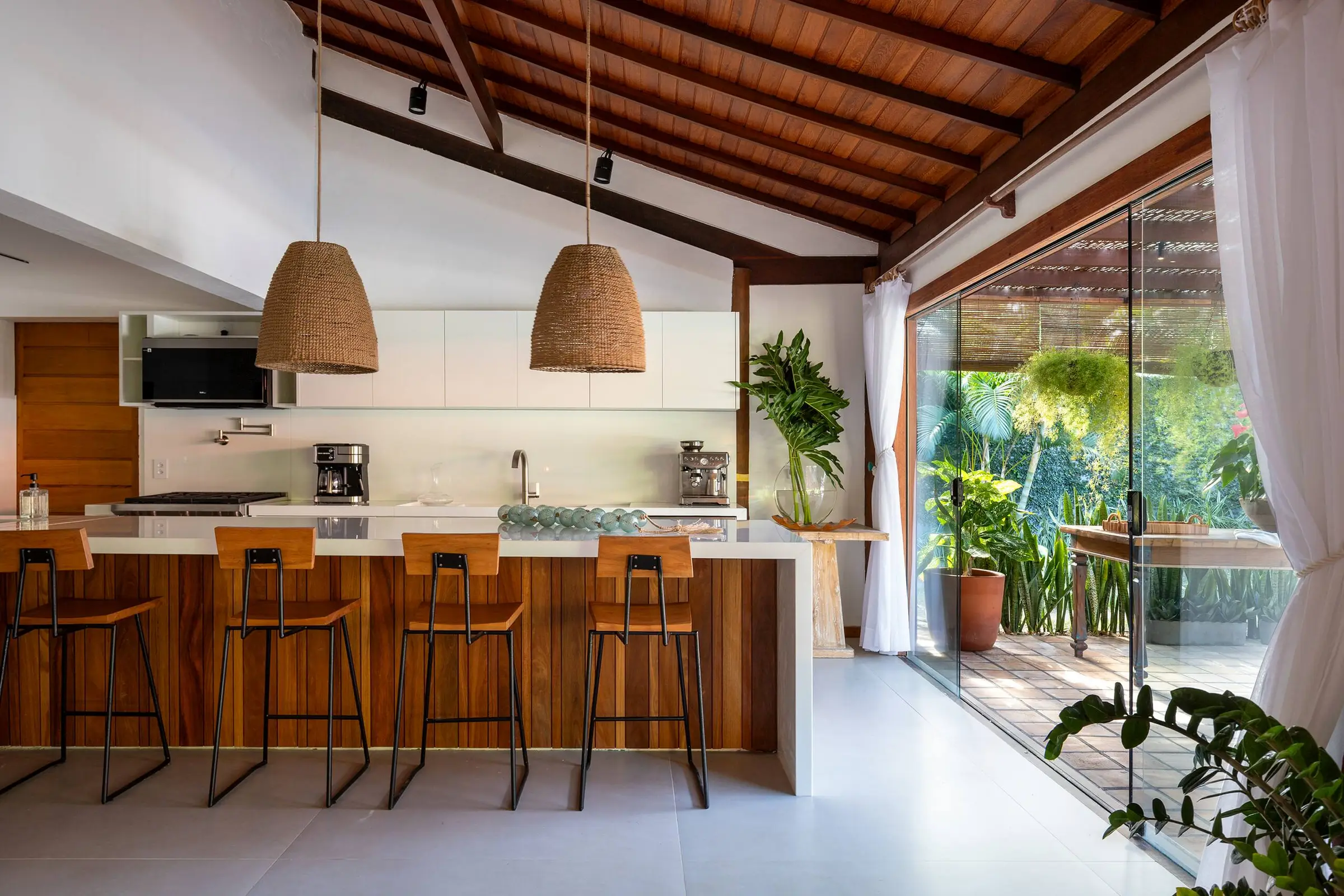 Bancada de cozinha com banquetas voltada para o jardim