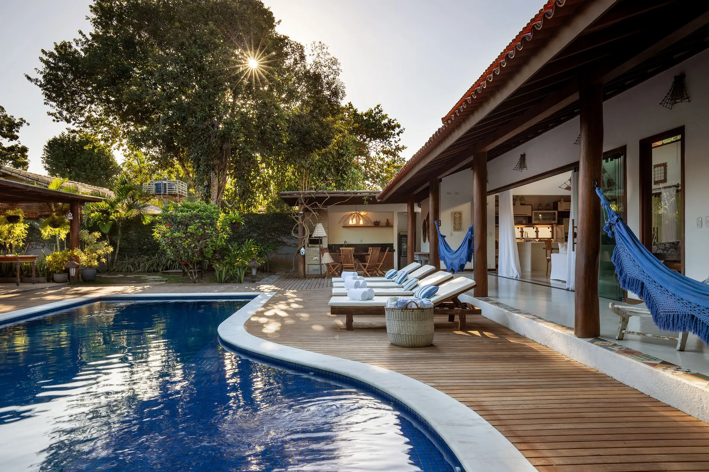 Piscina se estendendo entre as duas casas, espreguiçadeiras na borda